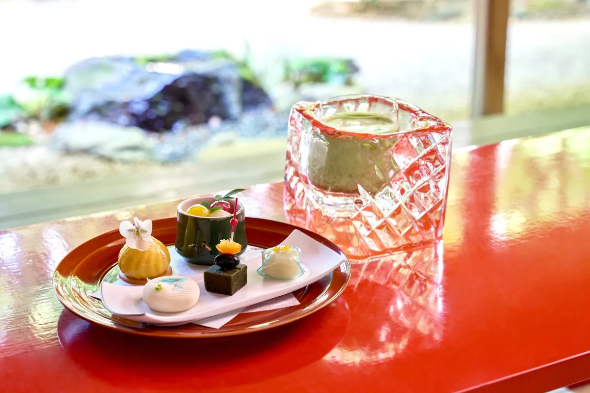 Matcha latte in a carved ice glass alongside Japanese sweets