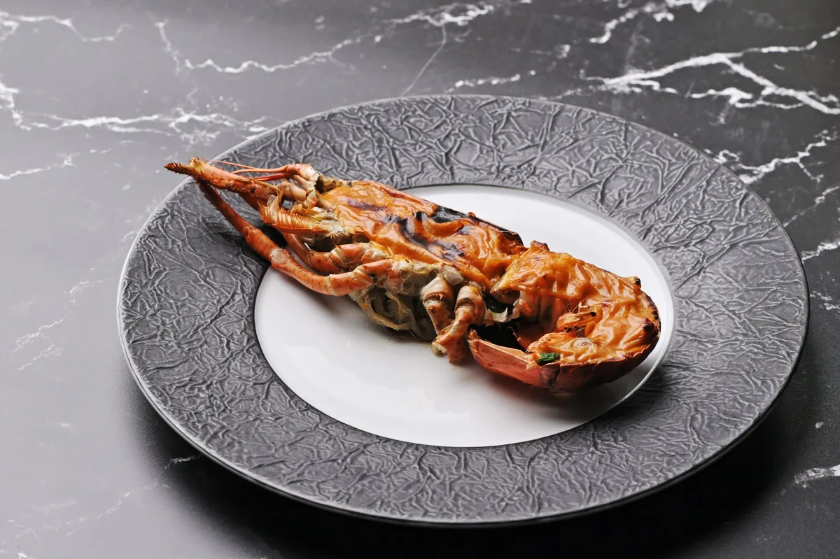 A whole lobster gratin on a textured plate