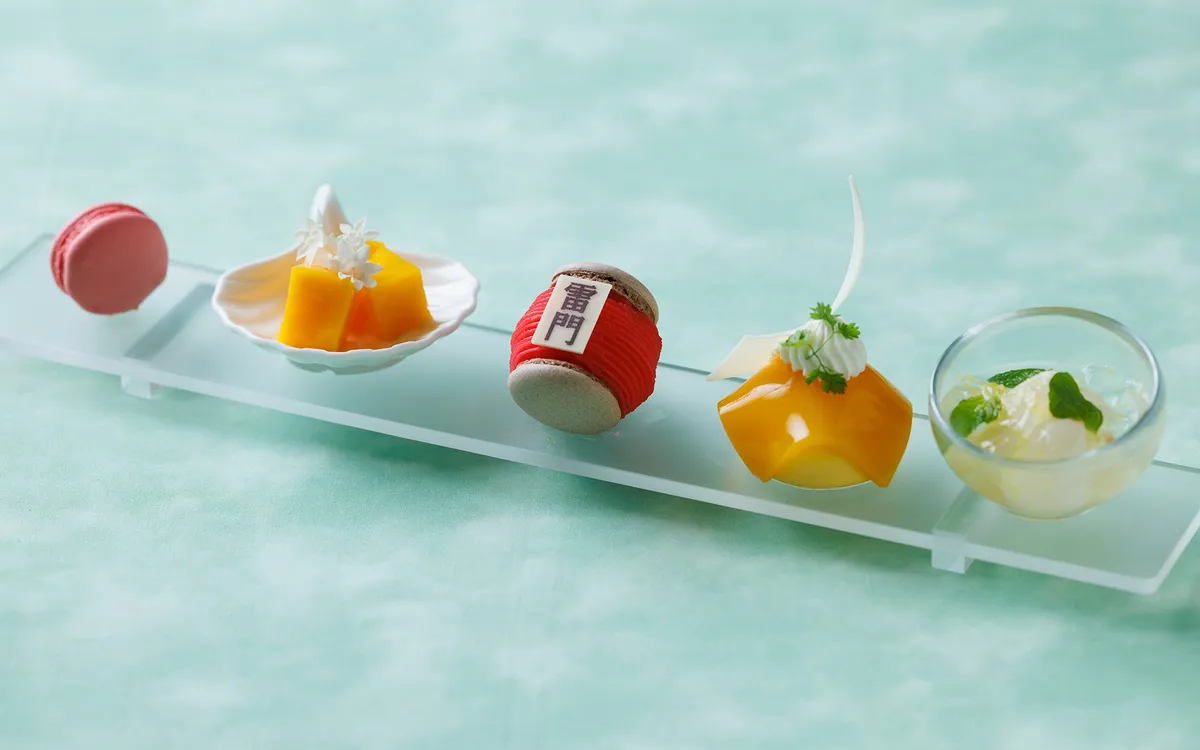 A close-up of various sweets including a macaron decorated with the Kaminarimon gate character.
