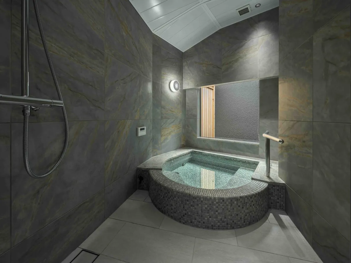 A stone-tiled bathroom with a forest view