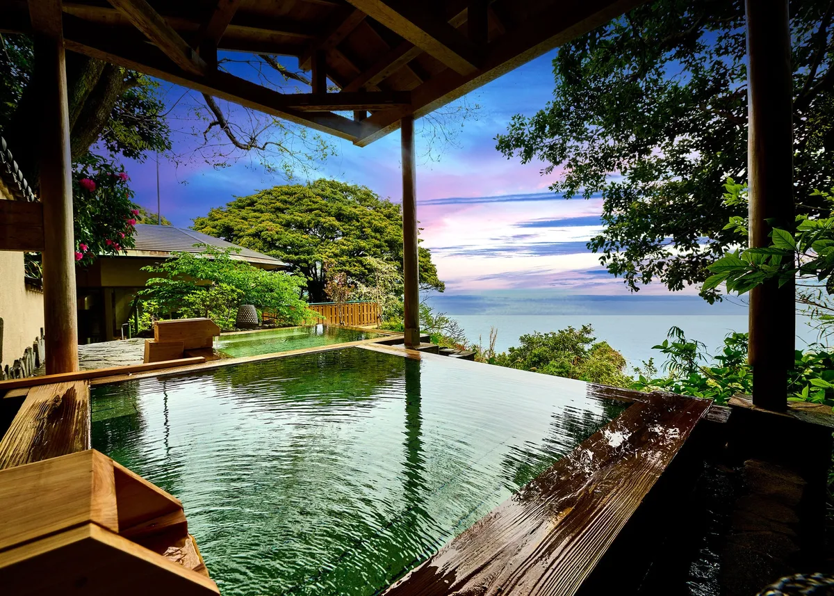 An open-air hot spring bath overlooking the ocean at dusk
