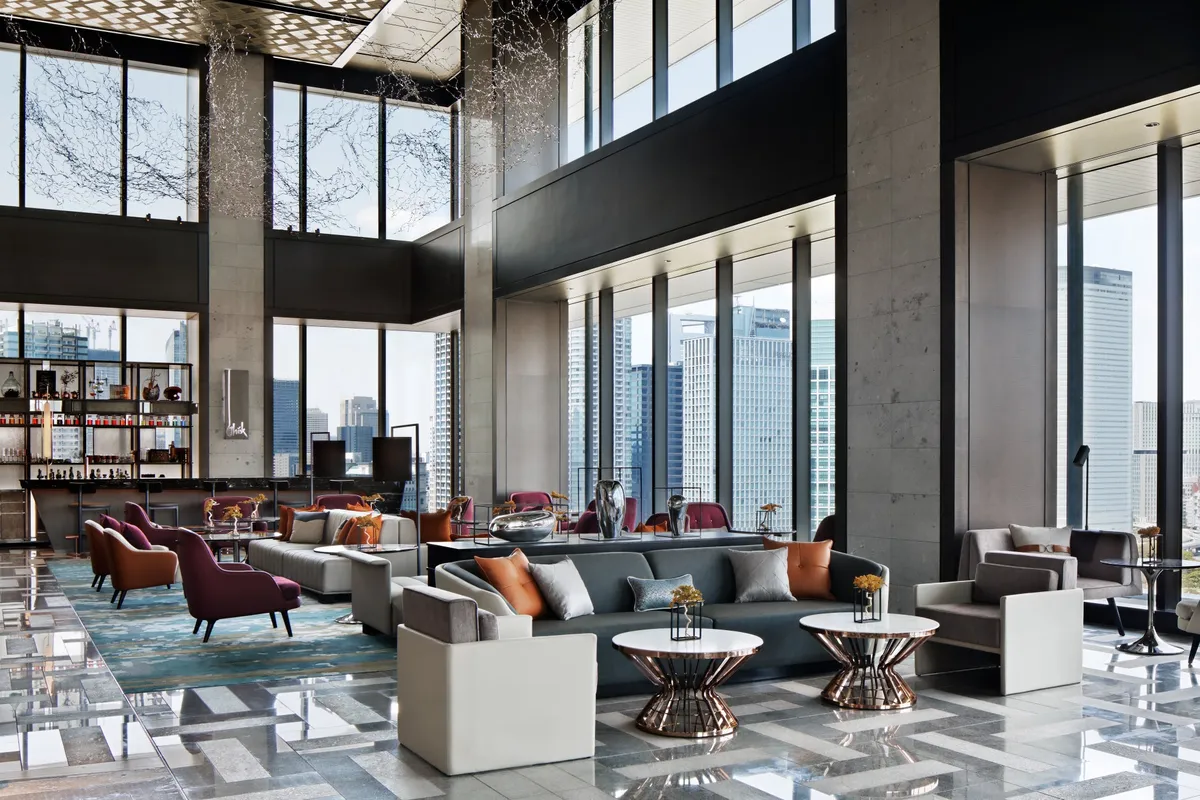 Modern lounge interior with high ceilings and panoramic windows overlooking the Tokyo skyline