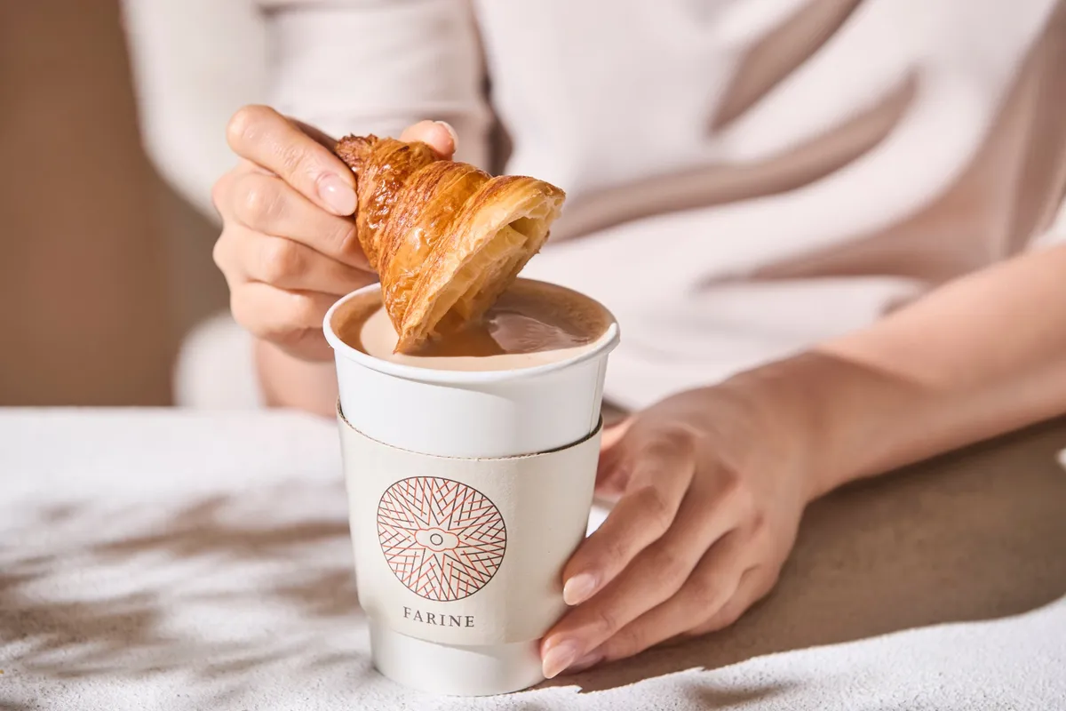 A croissant being dipped into a cup of coffee