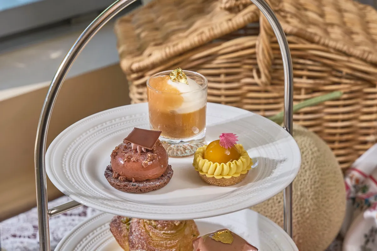 Top tier of afternoon tea with mango tart and chocolate dessert