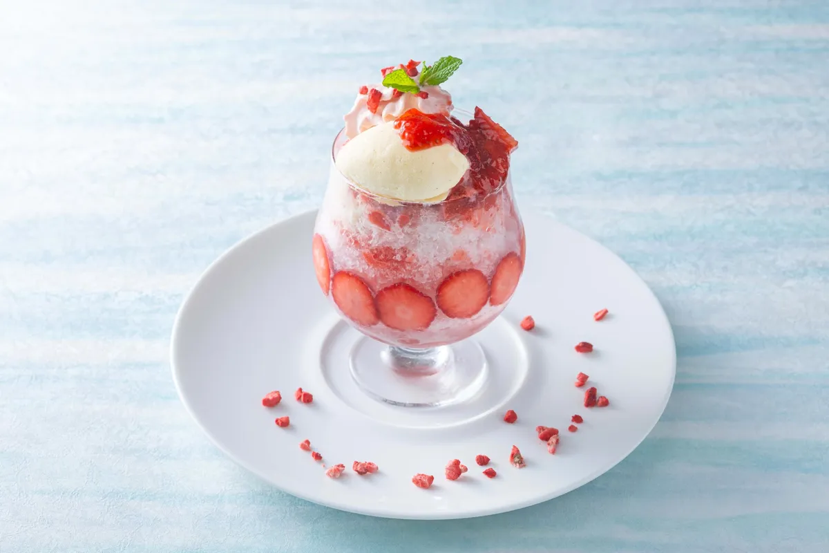 Strawberry Milk Kakigori served in a glass with vanilla espuma and fresh strawberries.