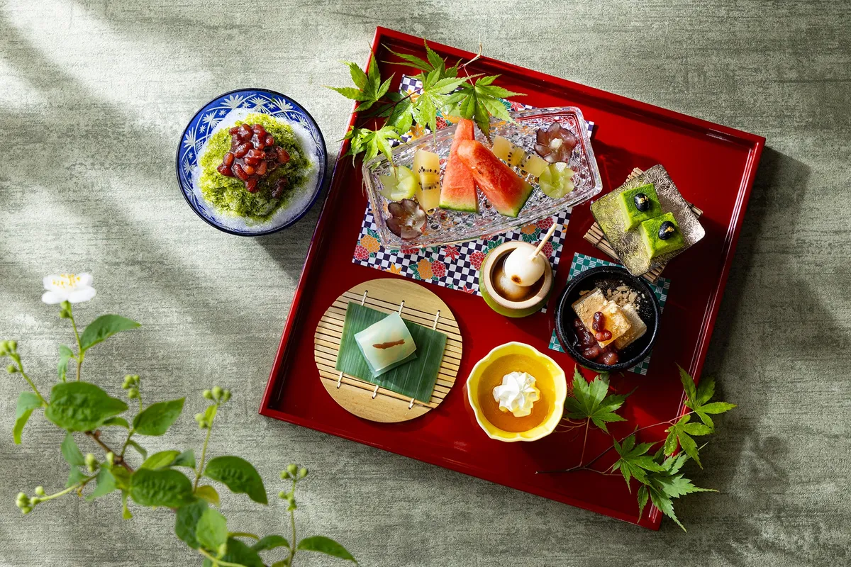 An overhead view of the red lacquer tray featuring traditional Japanese sweets and seasonal fruits