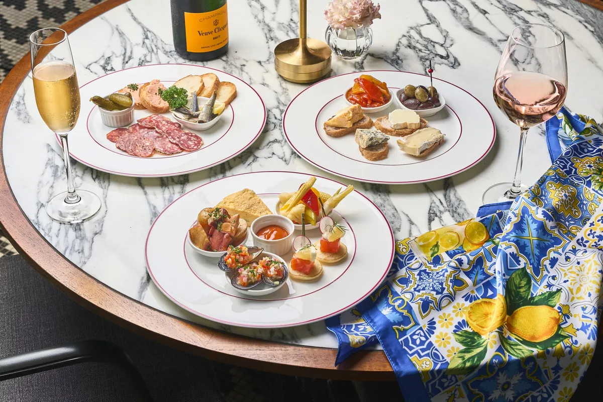 Three plates of Mediterranean appetizers including charcuterie and seafood