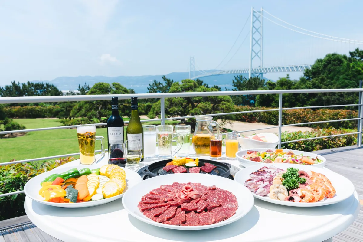 Barbecue spread and drinks set against the Akashi Kaikyo Bridge