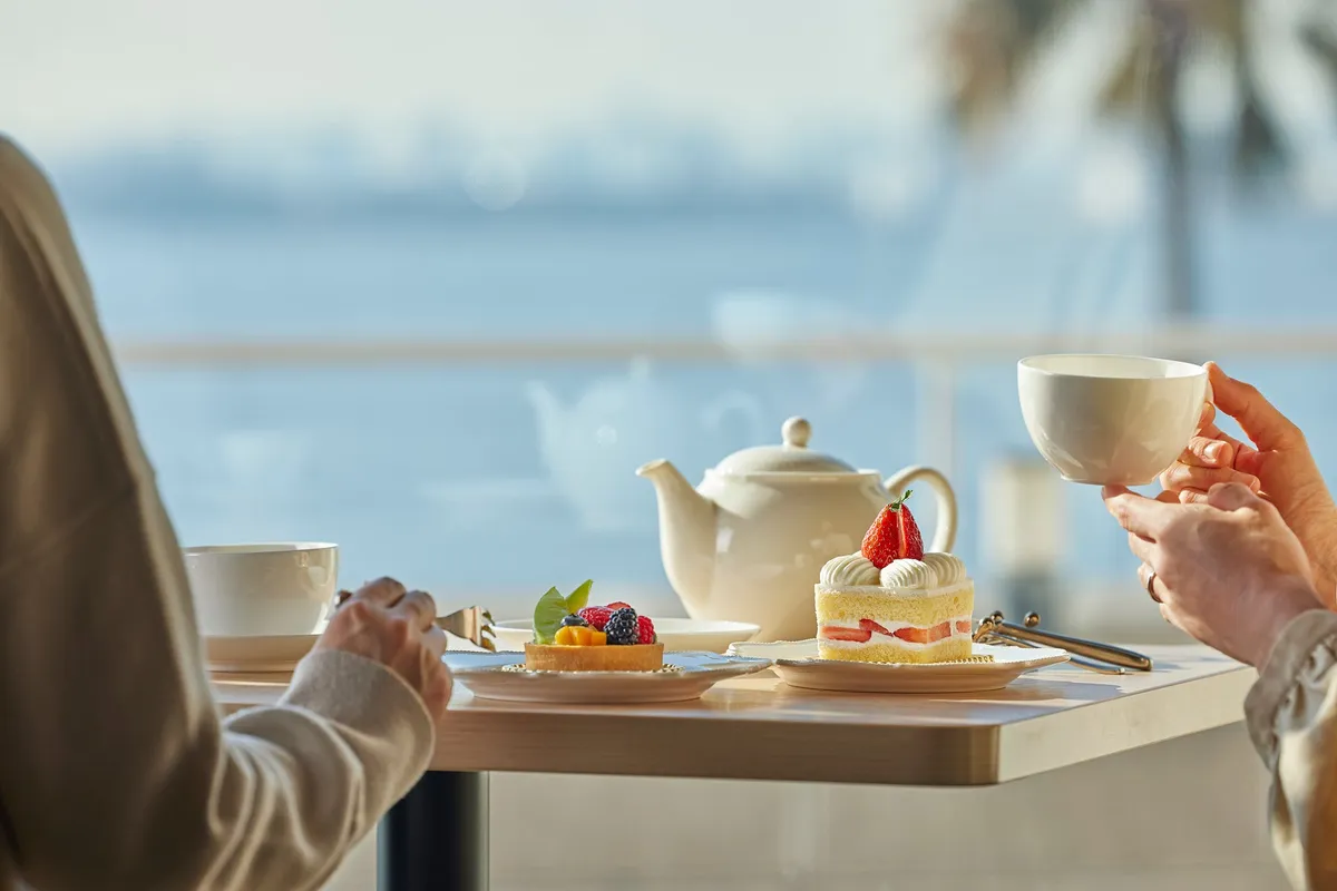 Guests enjoying tea and cake with a view of Tokyo Bay