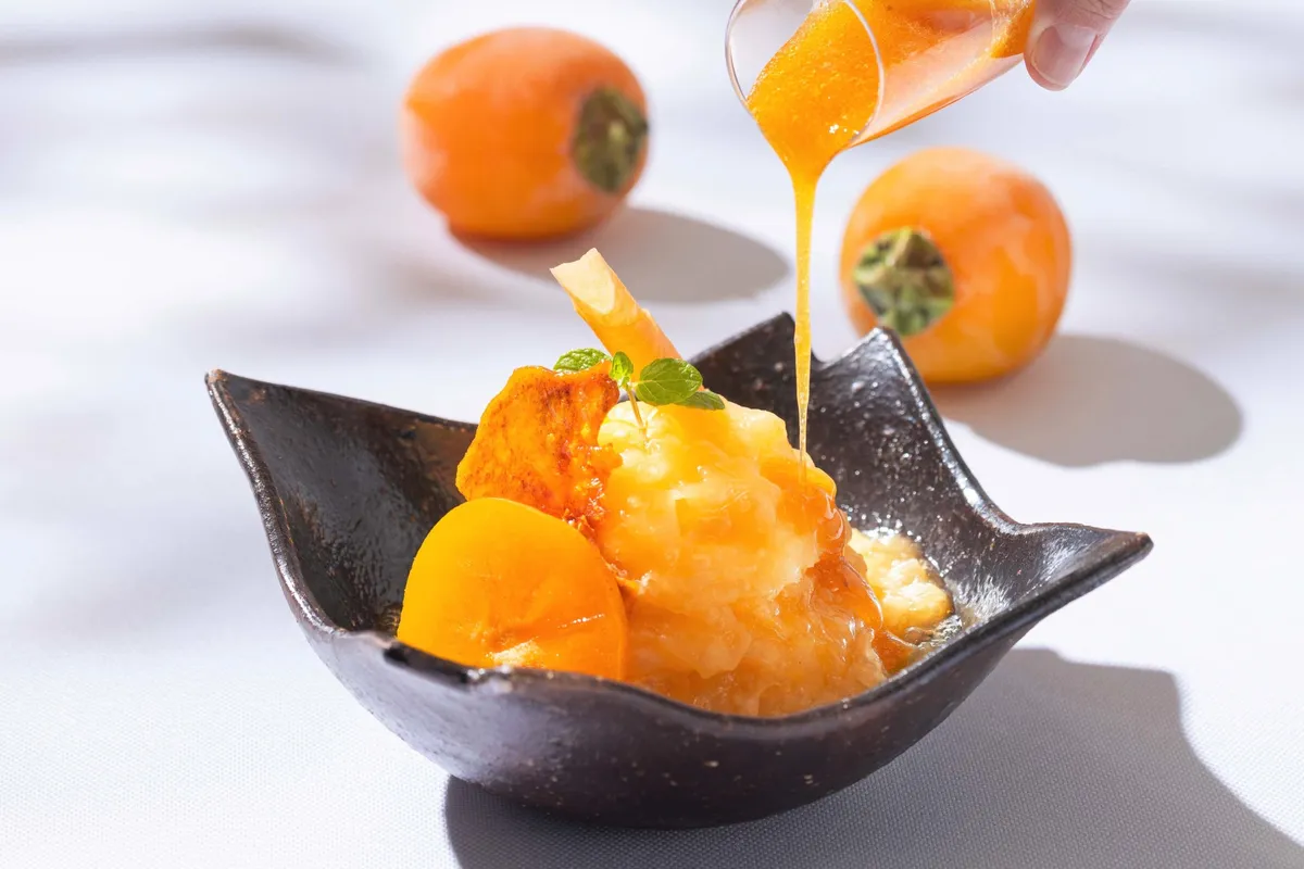 Persimmon Shaved Ice with syrup being poured over frozen fruit.