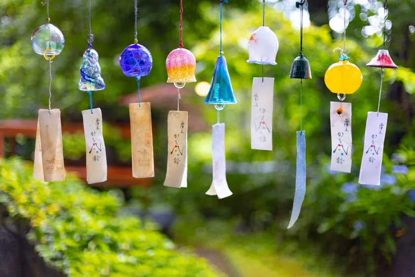 A row of colorful glass wind chimes hanging outdoors