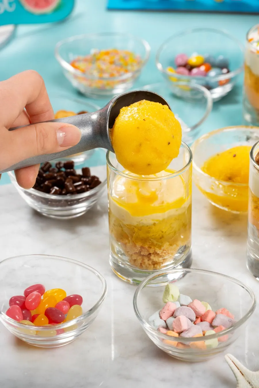 A chef scooping sorbet into a glass dessert vessel
