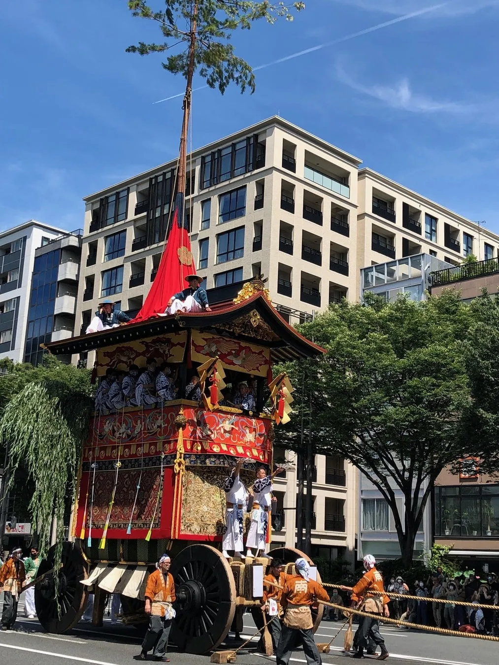 Men in traditional festival attire pulling the massive wooden float