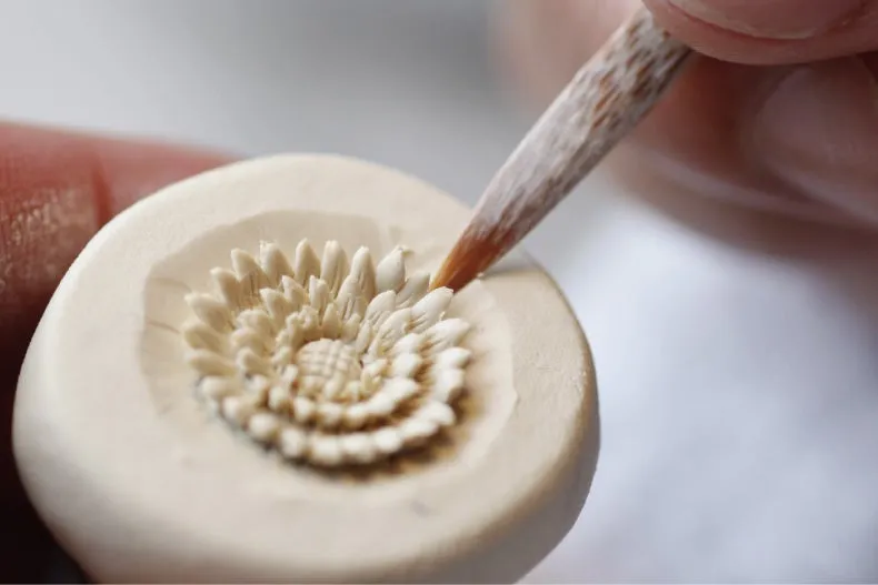 A craftsman carving a porcelain flower pattern