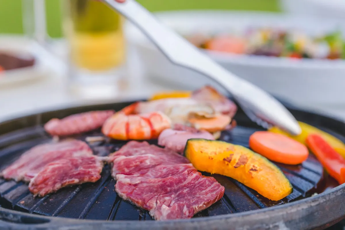 Meats and vegetables cooking on a tabletop grill