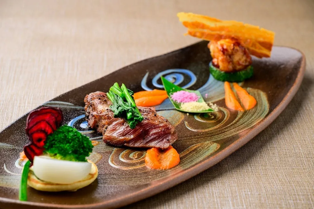 Miyagi beef served with colorful garnishes on a patterned rectangular plate.