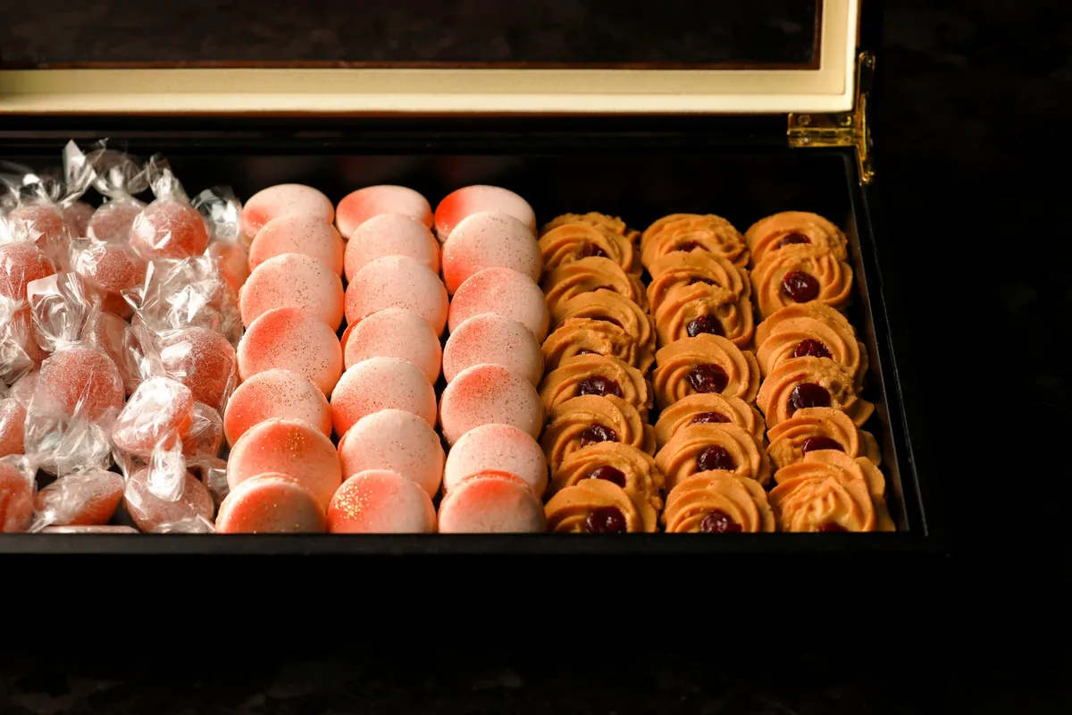 A box of peach-colored macarons and cookies