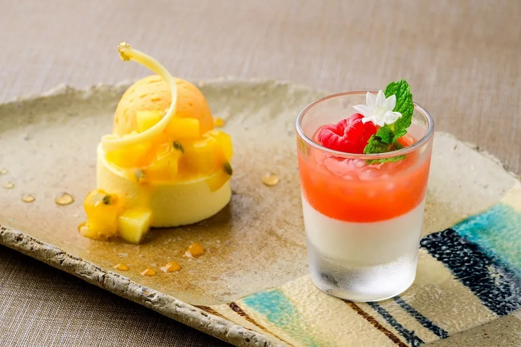 Tropical desserts including a panna cotta and fruit mousse on a rustic plate.