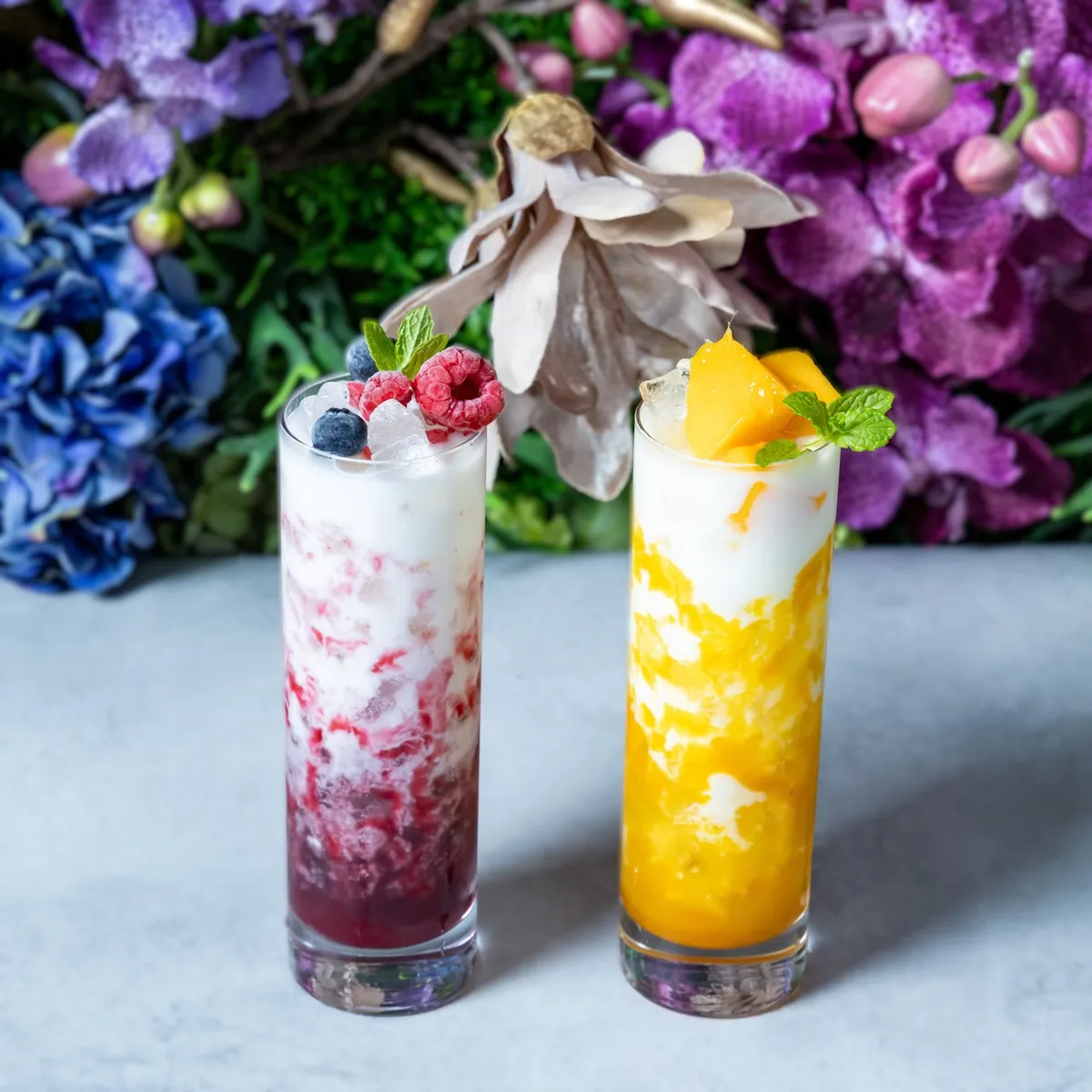 Two fruit lassis decorated with berries and mango