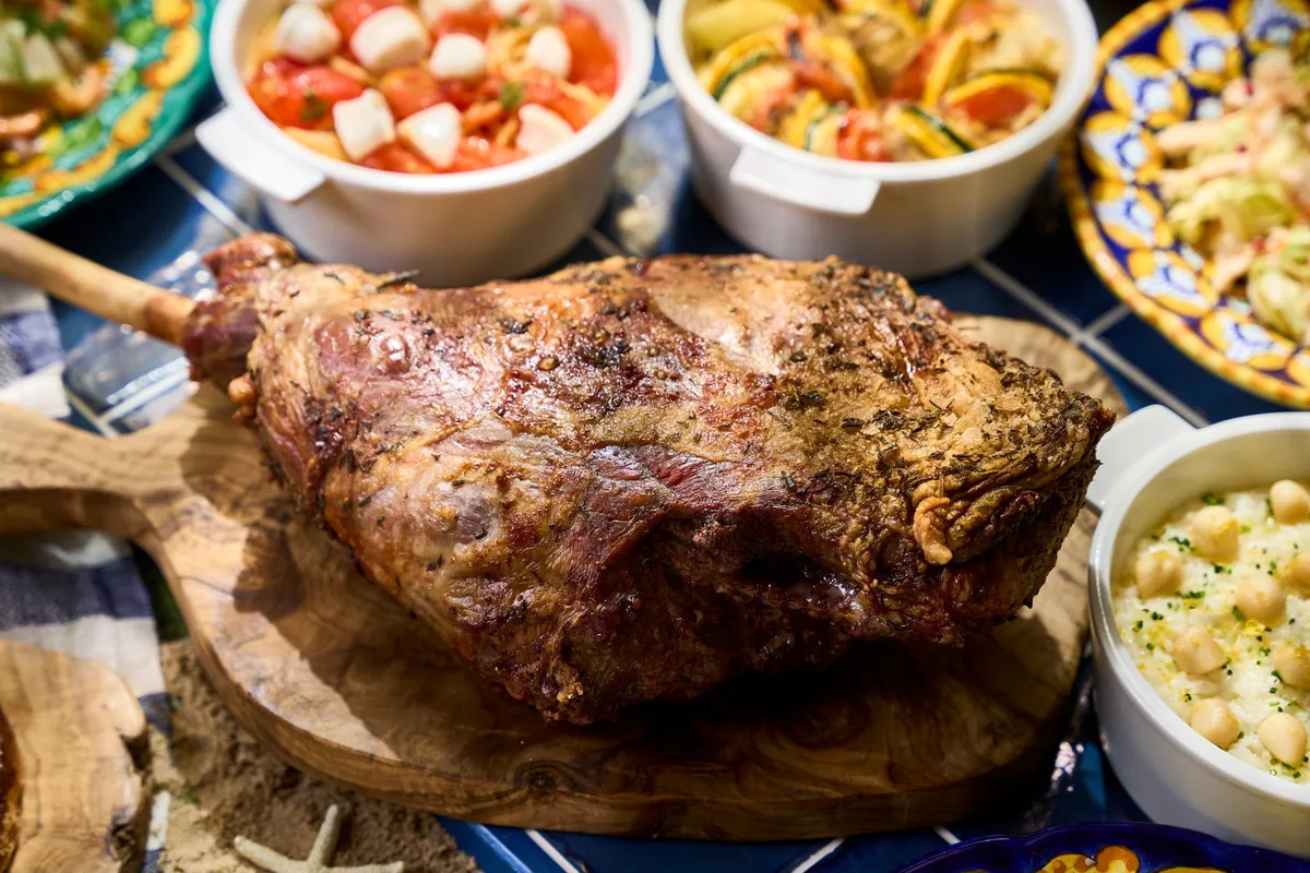 Roasted lamb leg with herbs on a wooden board