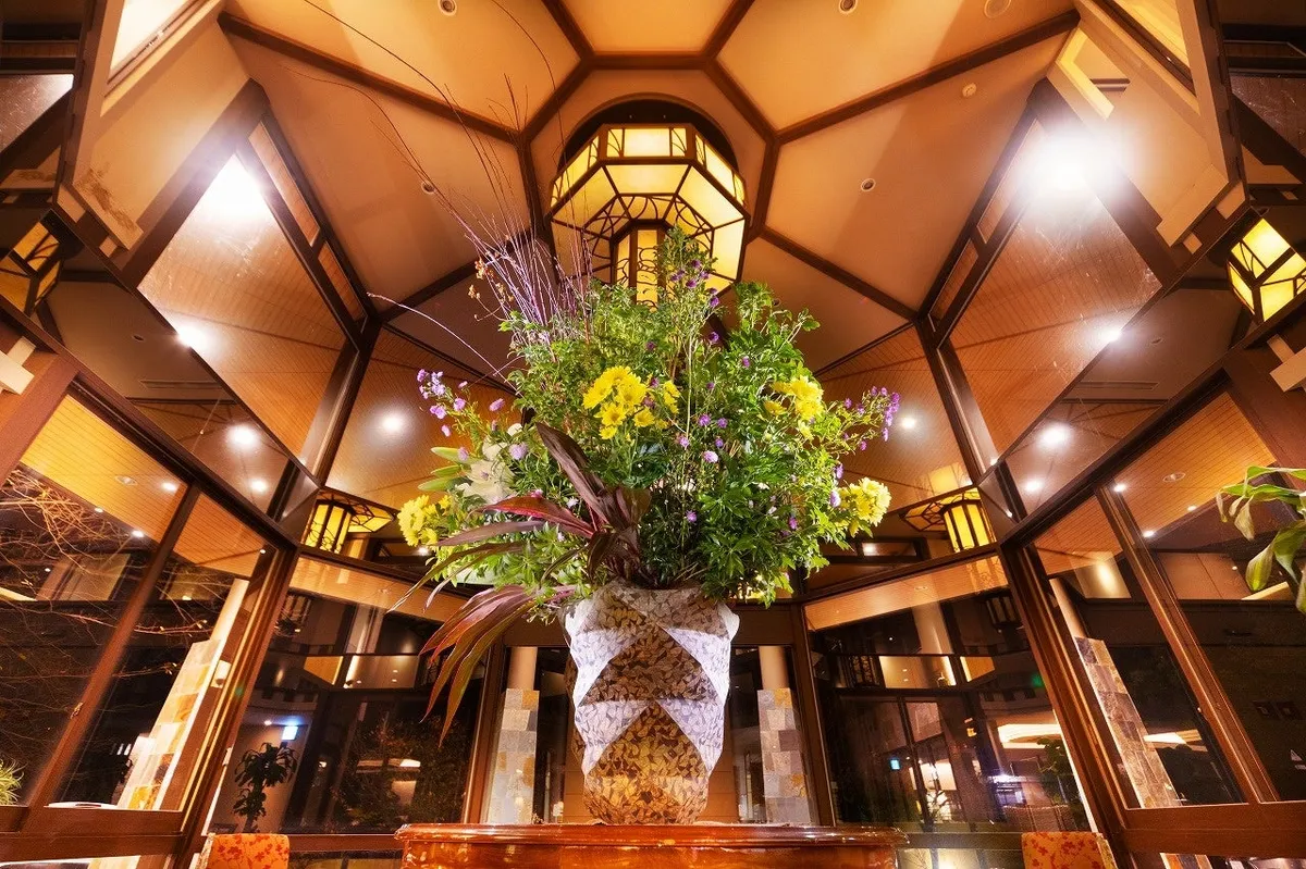 A large floral arrangement in a lobby with geometric wooden ceilings