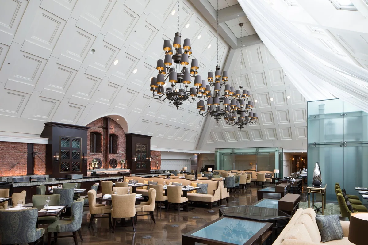 The Atrium dining area with a high glass ceiling and brick walls