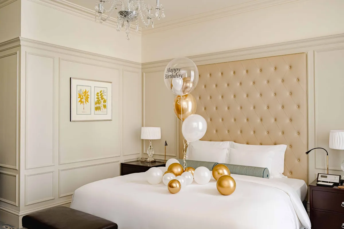 Gold and white birthday balloons on a guest bed