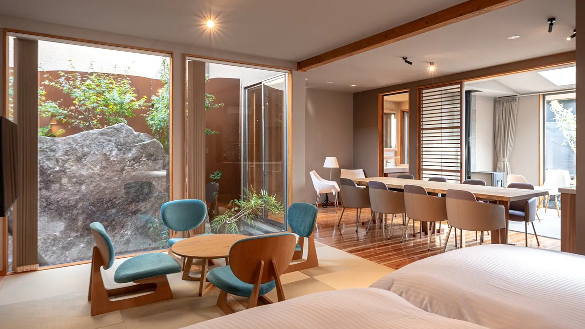 A dining and living space with floor-to-ceiling windows overlooking a rock garden.