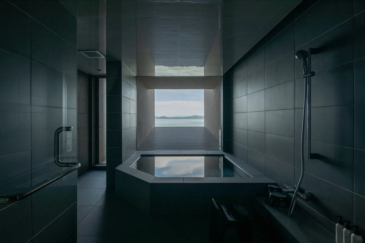 Minimalist indoor stone bath with lake view
