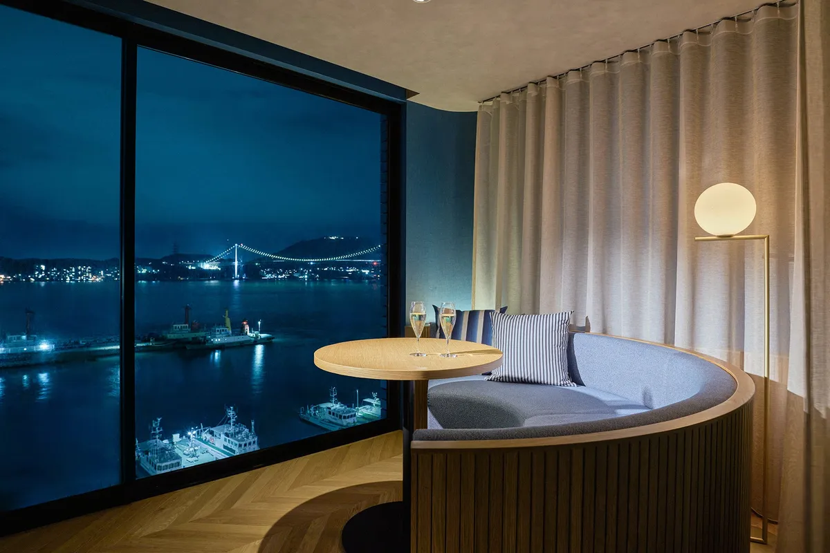 A guest room with a circular sofa and night views of the strait