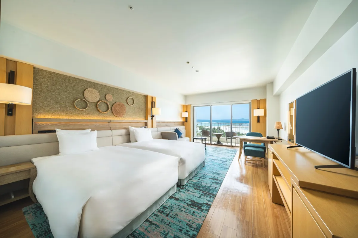 A guest room with twin beds and an ocean-view balcony