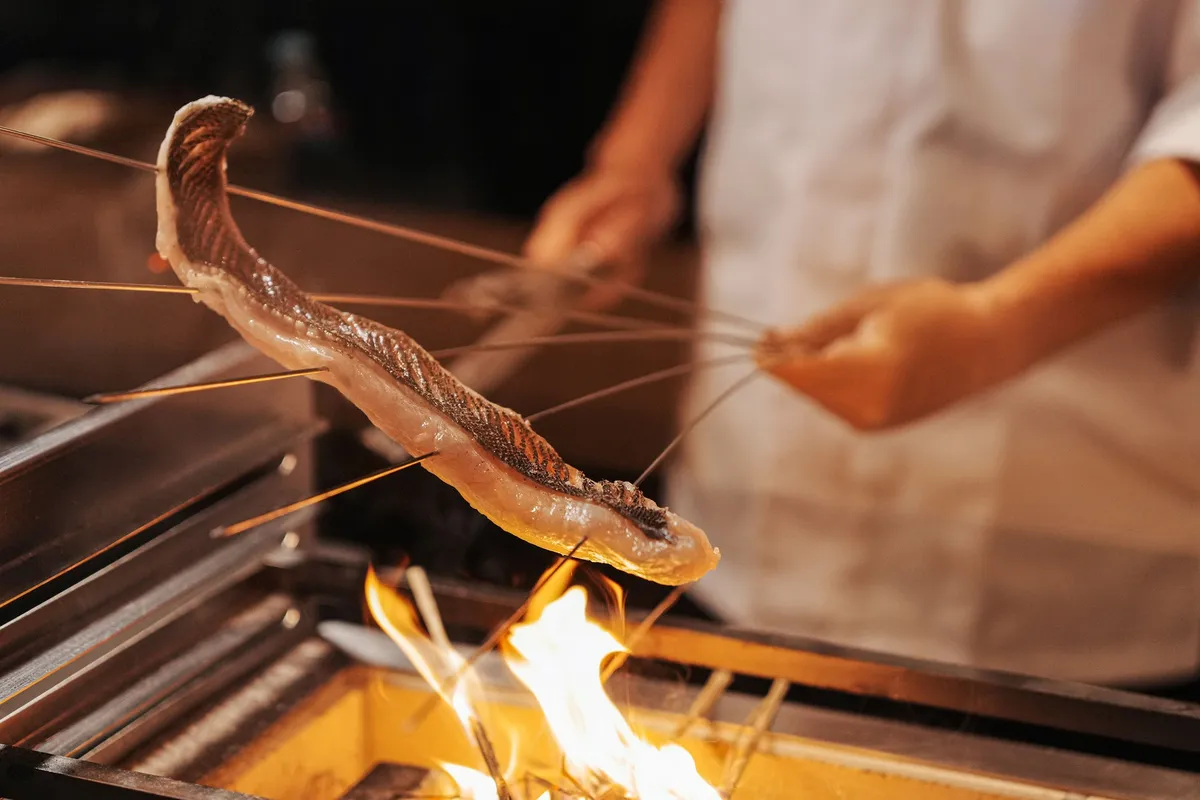 A chef preparing fresh seafood over a charcoal grill.