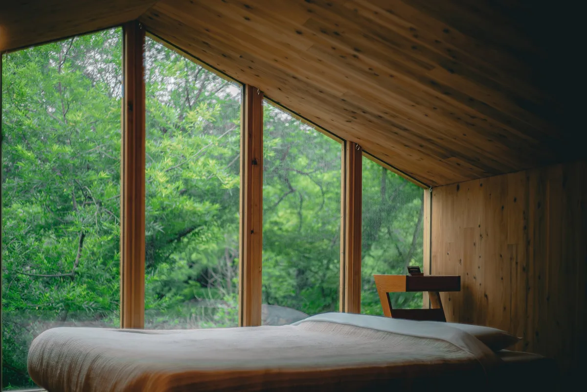 Interior bedroom view with large forest-facing window